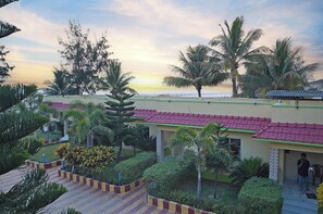 Un resort con diversi edifici, palme e vista sull'oceano al tramonto.