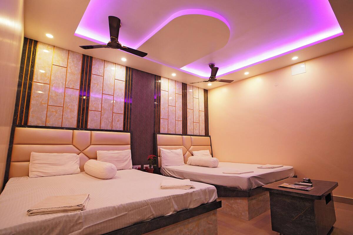 A hotel room with two beds, ceiling fans, and a small bedside table with a notebook.