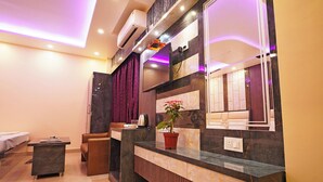 A modern reception area with a marble counter, a potted plant, and a large mirror. - Marino Beach Resorts (Kanthi)