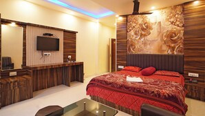 A modern hotel room with a large bed, a desk, a flat-screen TV, and a decorative wall panel. - Marino Beach Resorts (Kanthi)