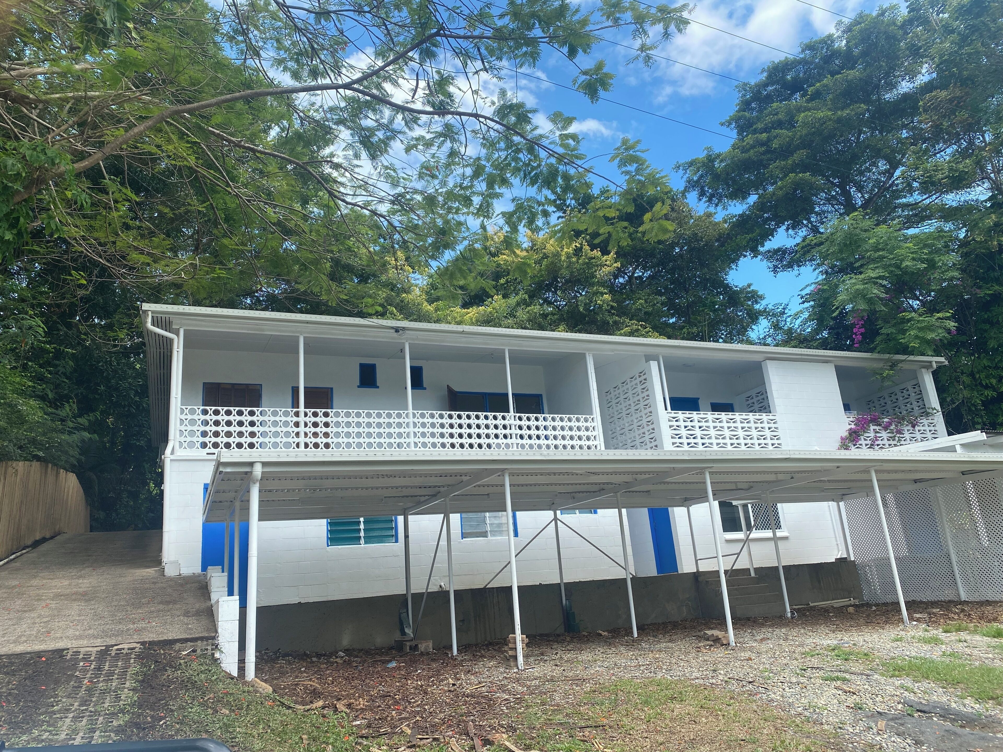 A two-story building with a covered balcony and a fenced yard.
