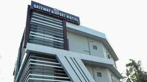 Ett modernt hotell vid flygplatsen, med en väl synlig skylt, en överbyggd entré och en gångväg med plattor.