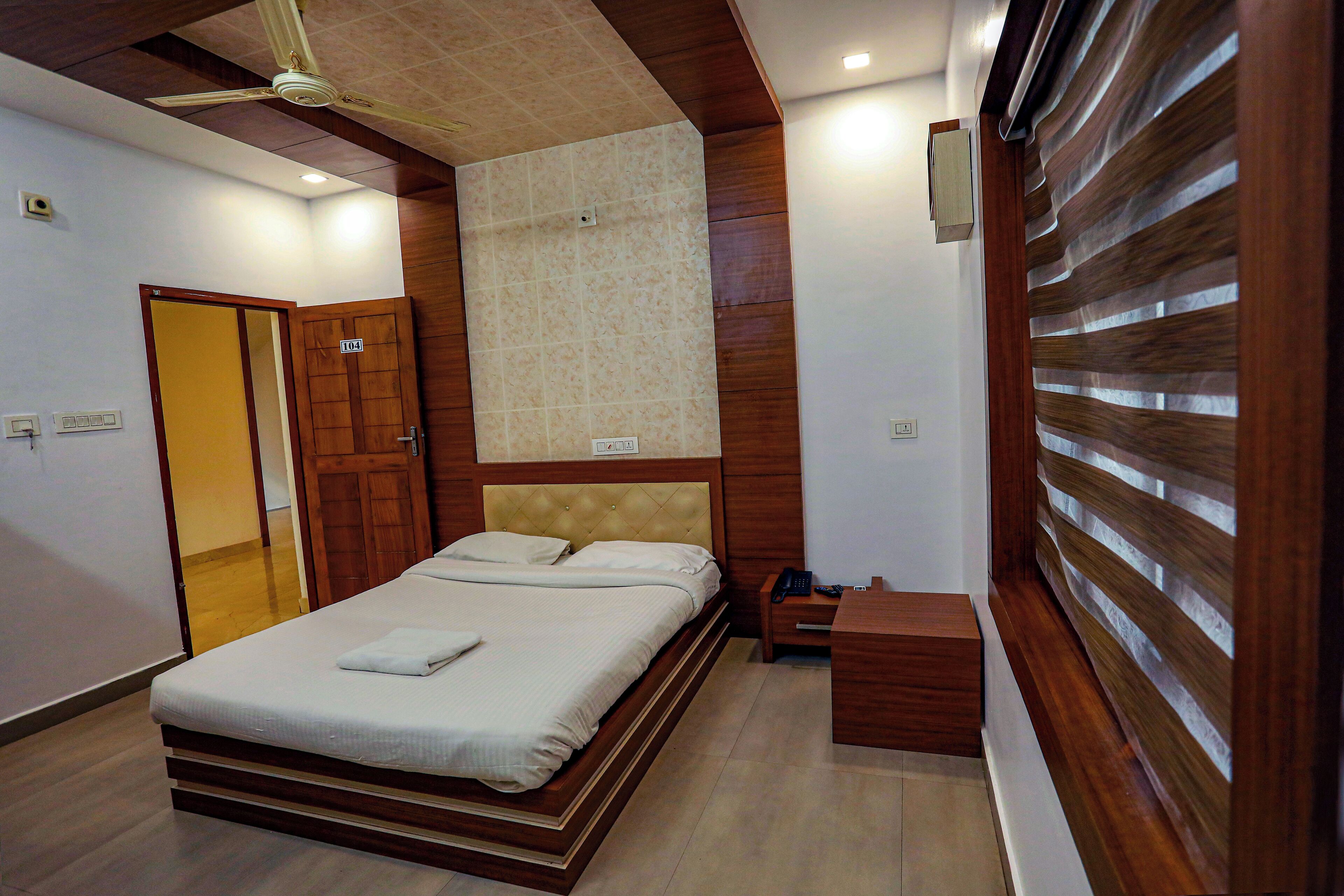 A bedroom with a bed, wooden headboard, bedside table, and a nightstand.