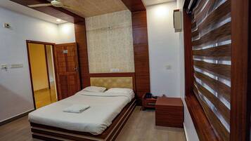 A bedroom with a bed, wooden headboard, bedside table, and a nightstand.