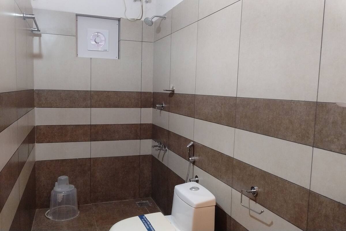 A small, tiled bathroom with a toilet, a shower, and a hand dryer.