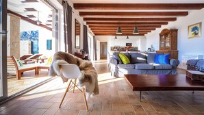 A spacious living area with a high ceiling, wooden beams, a large window, and a cozy seating arrangement. - Villa Family and friends, Dubravka (Dubravka)
