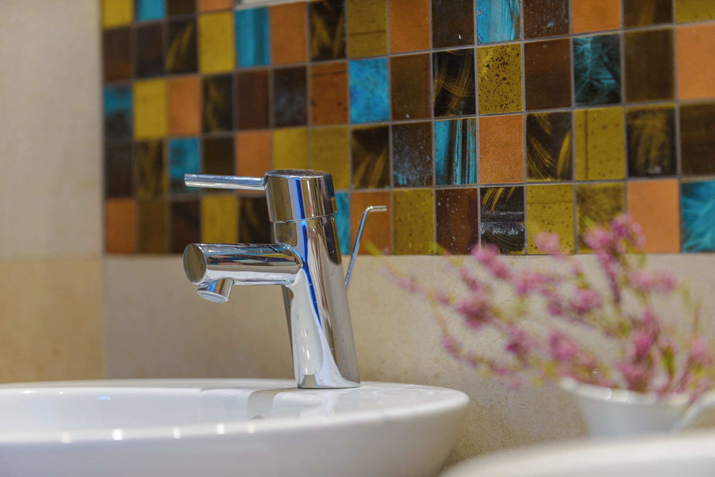 Un lavabo de salle de bain avec un robinet chromé et un pare-éclaboussures carrelé.