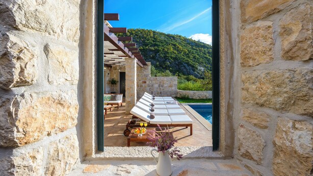 A stone-walled room with a view of a pool and a mountain. - Villa Family and friends, Dubravka (Dubravka)
