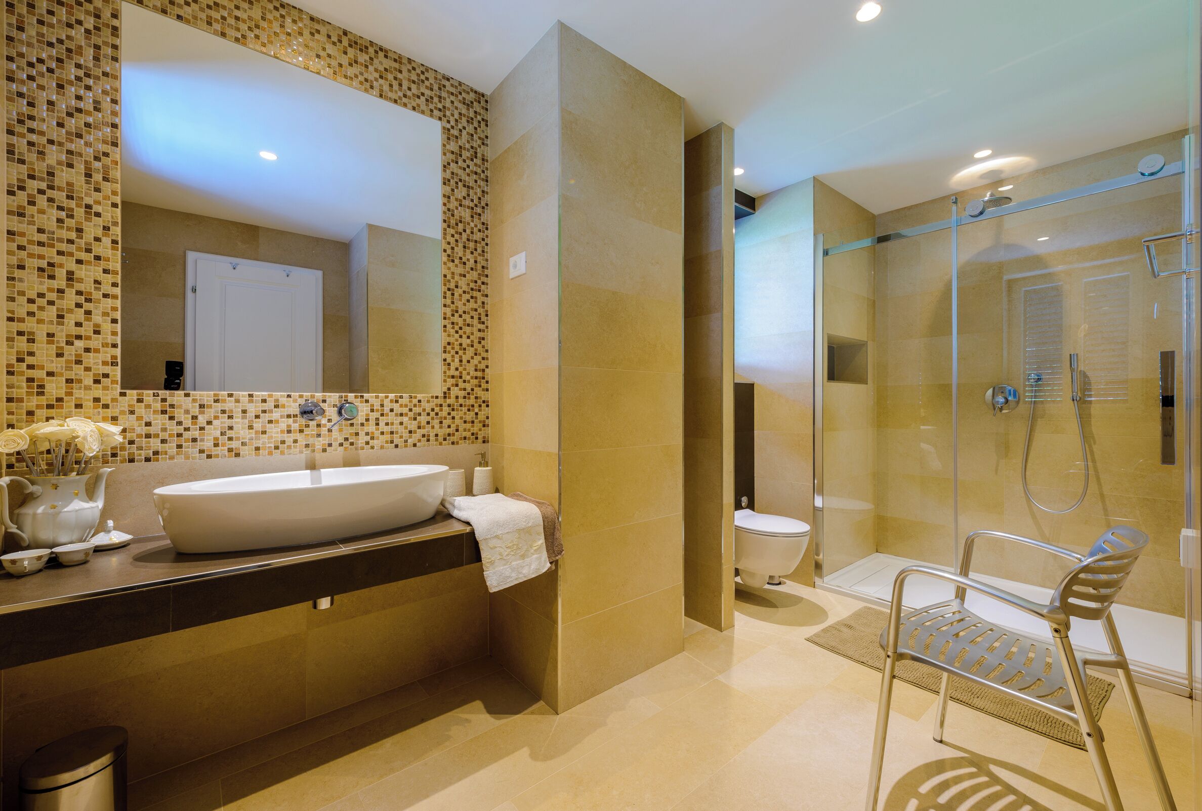 A modern bathroom with a large mirror, a sink, a toilet, and a shower area.