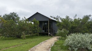 A modern house with a sloped roof, a wooden deck, and a gravel pathway leading to the entrance. - Sleep Whiskers Away From the Lions and " Feel " Them Roar! Cabin 3 (The Crags)