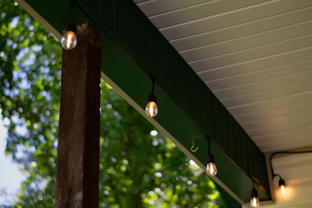 A string of exposed light bulbs hanging from a green structure with a white ceiling.