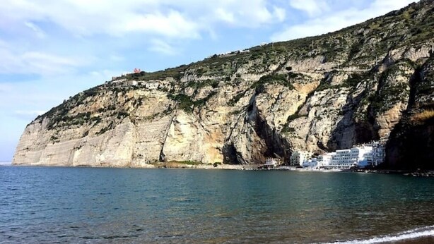 Um penhasco costeiro com edifícios no topo, com vista para um mar calmo.