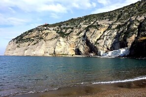 A coastal cliff with buildings on top, overlooking a calm sea.