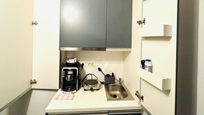 Une cuisine compacte équipée d’une machine à café, d’une bouilloire et d’un évier.