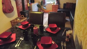 Un coin repas avec une table dressée pour quatre personnes, comprenant des serviettes et des couverts rouges.