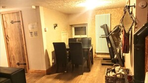 Un salon confortable avec une cheminée, un coin repas équipé d’un téléviseur et un tapis de course.
