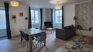 A modern living room with a dining area, large windows, and patterned wallpaper. - RENOVATED HOUSE SLEEPS 6 - SPACIOUS LIVING ROOM - WI-FI - FREE PARKING (Arthun)