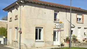 A building with a beige facade, a tiled roof, and a sign indicating directions to 'CEZAY' and 'ST SIME'. - RENOVATED HOUSE SLEEPS 6 - SPACIOUS LIVING ROOM - WI-FI - FREE PARKING (Arthun)