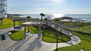 A coastal promenade with a gazebo, seating areas, and a curved walkway leading to the beach. - Seascape 1313 2 Bedroom Condo (Galveston)