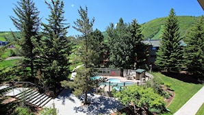 A pool area surrounded by trees, with a building in the background. - Snow Flower 123 3 Bedroom Condo (Park City)