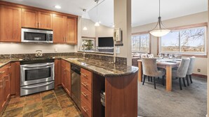 A modern kitchen with wooden cabinets, stainless steel appliances, and a granite countertop. - Snow Flower 123 3 Bedroom Condo (Park City)