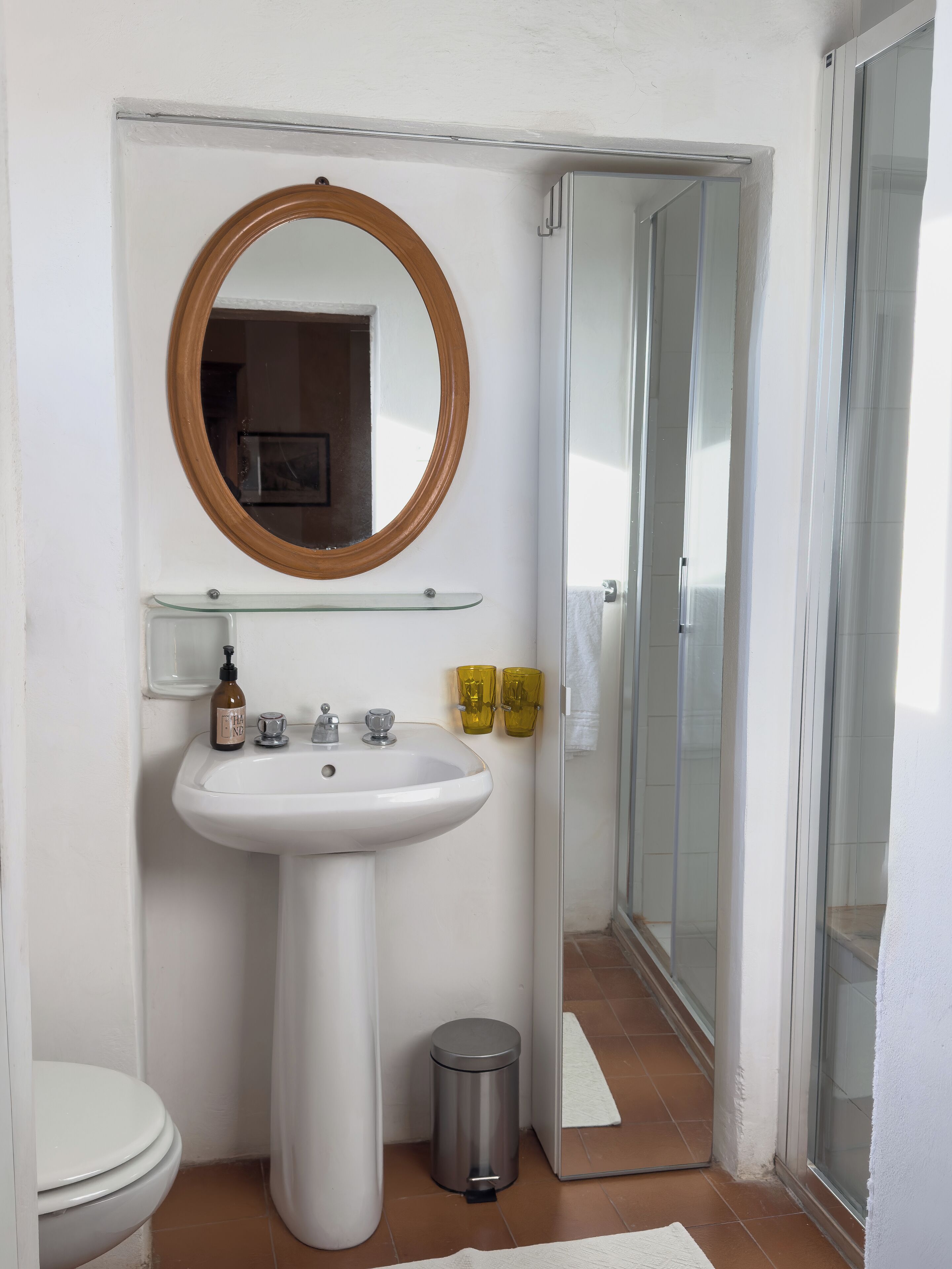 Une salle de bain avec un lavabo blanc, un miroir, des toilettes et une cabine de douche en verre.