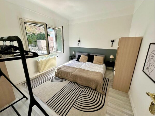 A bedroom with a bed, a radiator, a window, and a door.