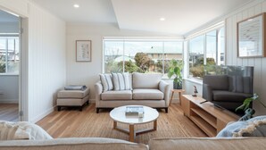 Un salon moderne avec un canapé beige, une table basse et un téléviseur posé sur un meuble en bois.