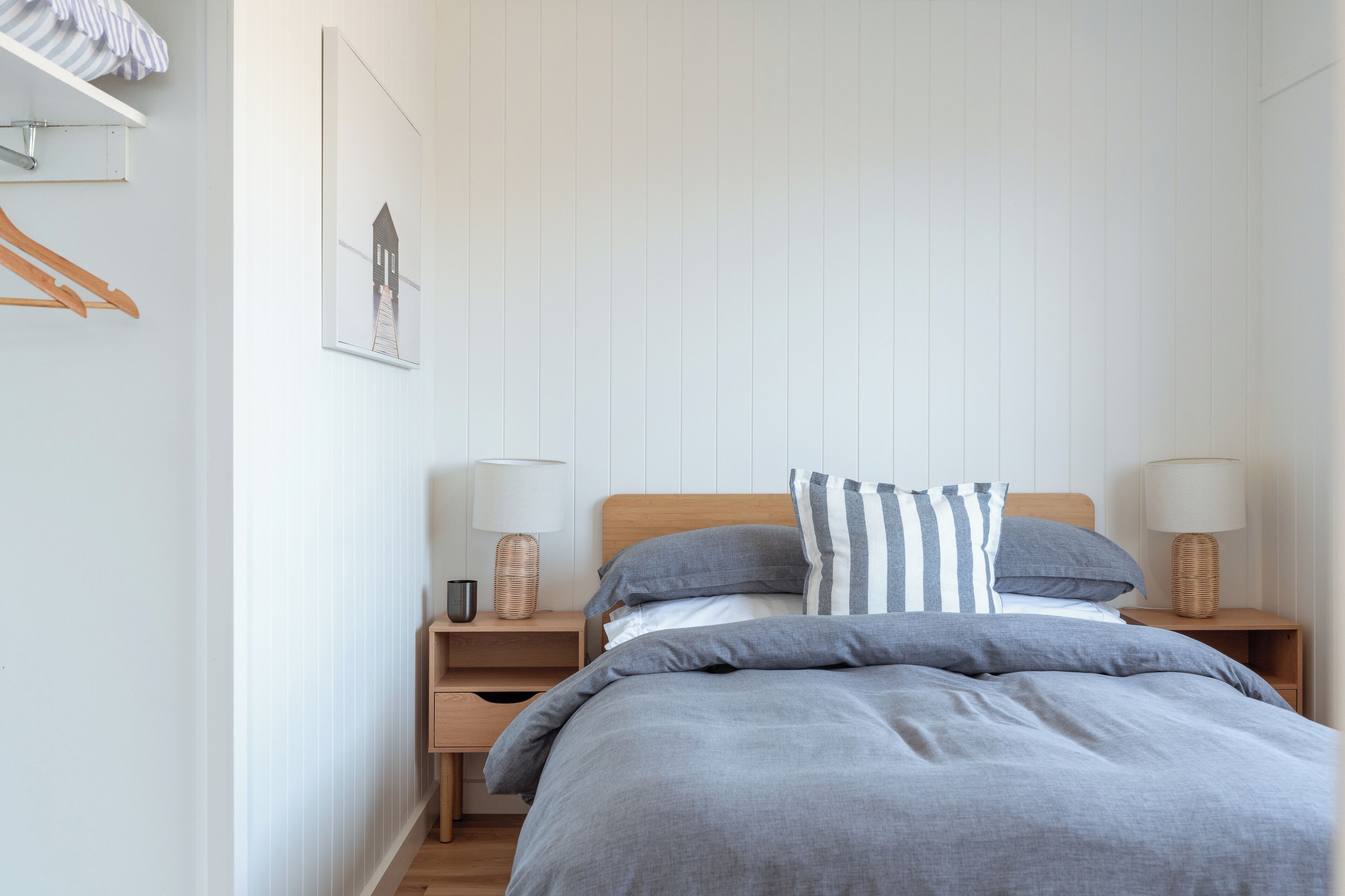 A neatly arranged bedroom with a bed, two bedside tables, and a wall-mounted shelf.