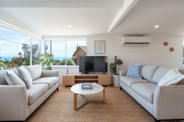 Una sala de estar moderna con dos sofás, una mesa de centro y un televisor.