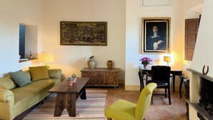 A cozy living room with a sofa, a chair, a coffee table, and a fireplace. - Walnut House (Toscana)