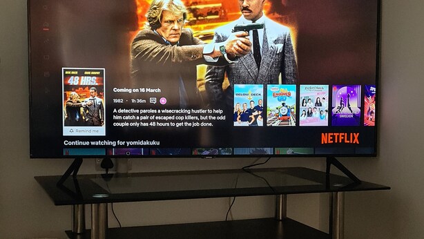 Televisió que mostra una interfície de Netflix amb un cartell de pel·lícula per '48 HRS' i programació pròxima.