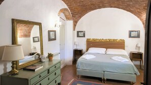 Een kamer met een bed, een dressoir, een spiegel en een lamp.