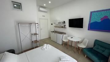 Una camera d'albergo con un letto, una scrivania, una sedia, un divano, una televisione e un angolo cottura.
