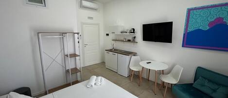 Une chambre d’hôtel équipée d’un lit, d’un bureau, d’une chaise, d’un canapé, d’une télévision et d’un petit coin cuisine.