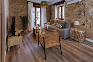 Una sala de estar acogedora con un sofá, un sillón de mimbre, un televisor y una lámpara.