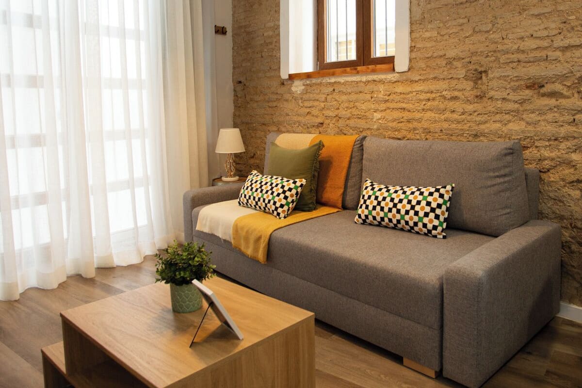 A modern living room with a grey sofa, wooden coffee table, and a hanging green lamp.