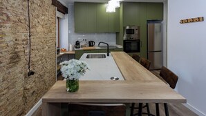A kitchen with a central island, green cabinets, and modern appliances. - Tenerias Apart Corp S.L (Valencia)