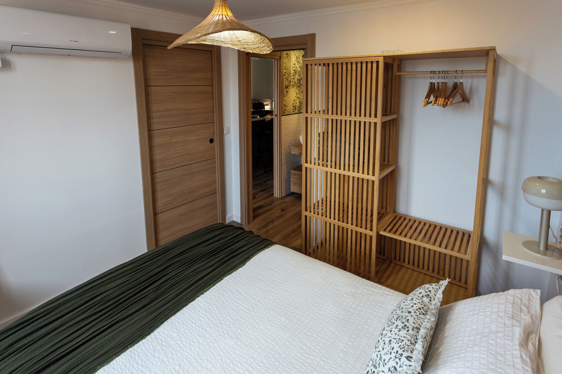 A bedroom with a bed, a wardrobe, and a hanging light fixture.