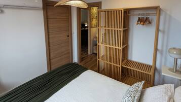 A bedroom with a bed, a wardrobe, and a hanging light fixture.