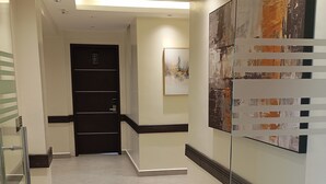 A hallway with a modern design, featuring a glass partition, a door with a number plate, and artwork on the walls. - Zuri Place Hotel Limited (Oyugis)