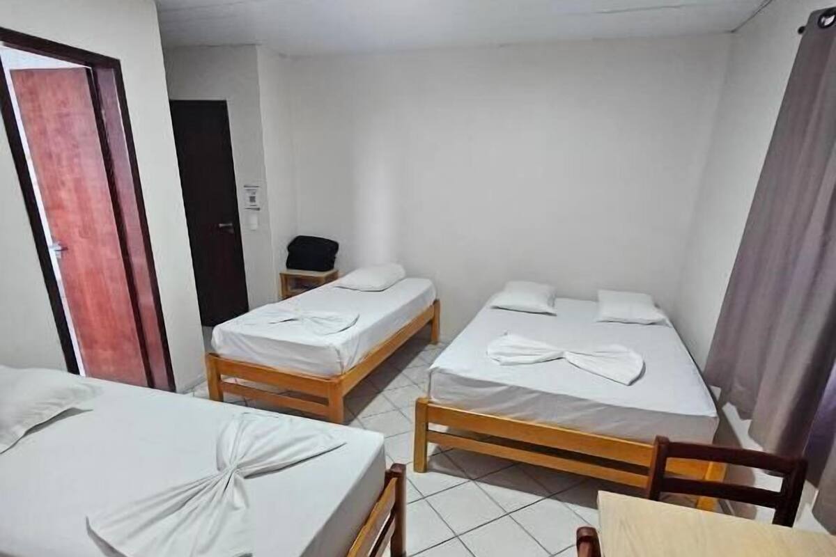 A hotel room with two single beds, a wooden table, a chair, and a desk.