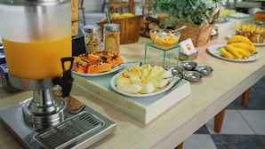 A buffet table with a fruit and vegetable display, a coffee machine, and various condiments. - Ok Inn Hotel Florianópolis (Florianópolis)