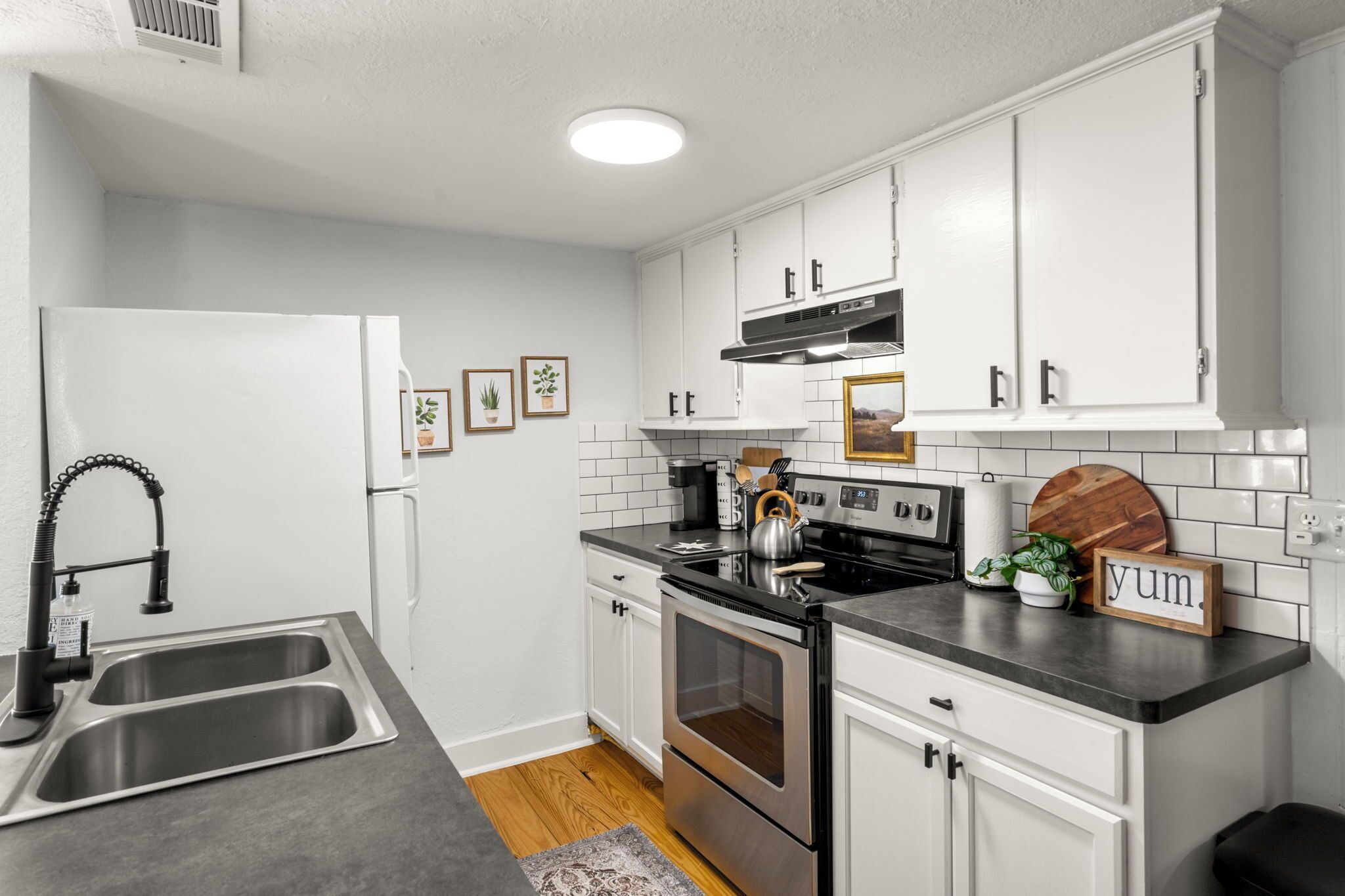 A modern kitchen with white cabinets, stainless steel appliances, and a black countertop.