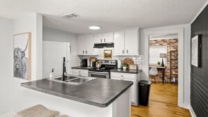 A modern kitchen with white cabinets, a stainless steel sink, and a granite countertop.