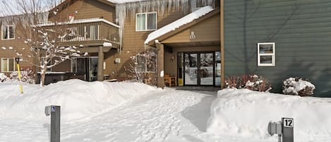 Edificio residencial con entrada cubierta de nieve y rampa accesible para sillas de ruedas.