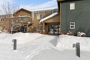 Edificio residencial con entrada cubierta de nieve y rampa accesible para sillas de ruedas.