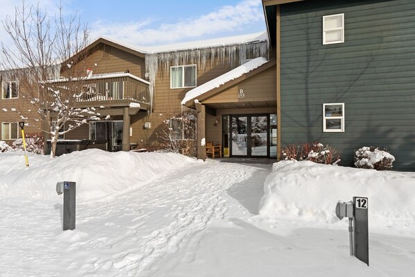 A residential building with a snow-covered entrance and a wheelchair-accessible ramp.