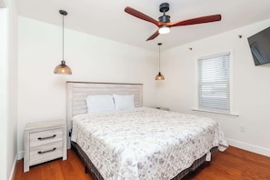 A bedroom with a bed, a nightstand, a ceiling fan, and a window with blinds. - Condo with Tiki Bar, Walk to Beach (Ocean City)