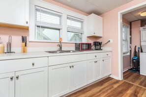A kitchen with white cabinets, a microwave, a coffee maker, and a vacuum cleaner.